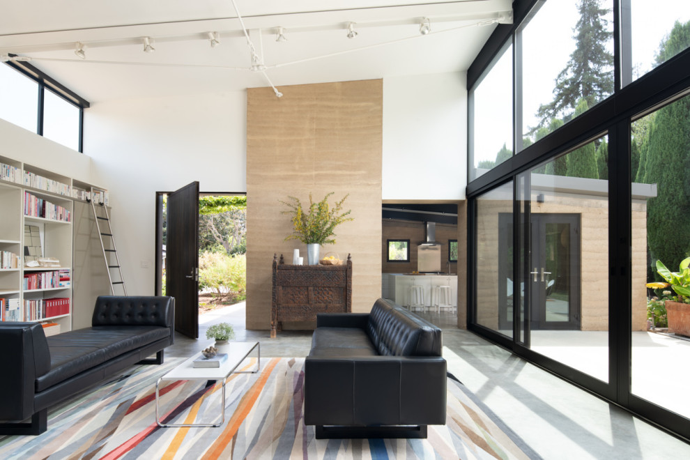 This is an example of a contemporary open plan living room in San Francisco with white walls, grey floors and a vaulted ceiling.