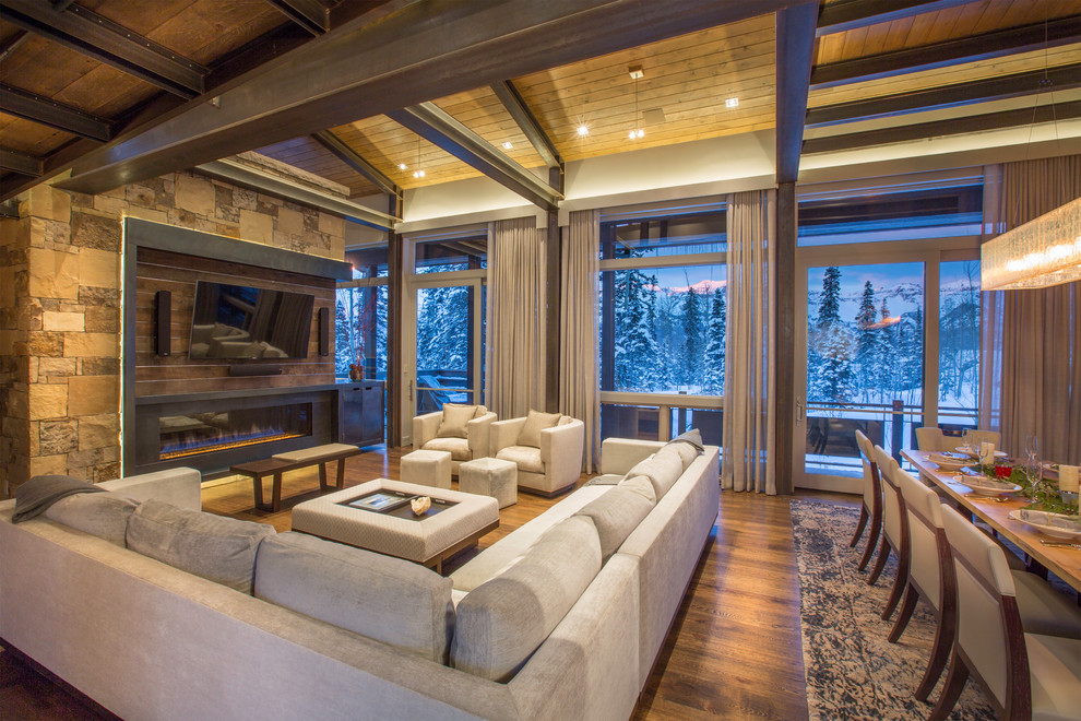 Esempio di un ampio soggiorno moderno aperto con pavimento in legno massello medio, cornice del camino in metallo e TV a parete