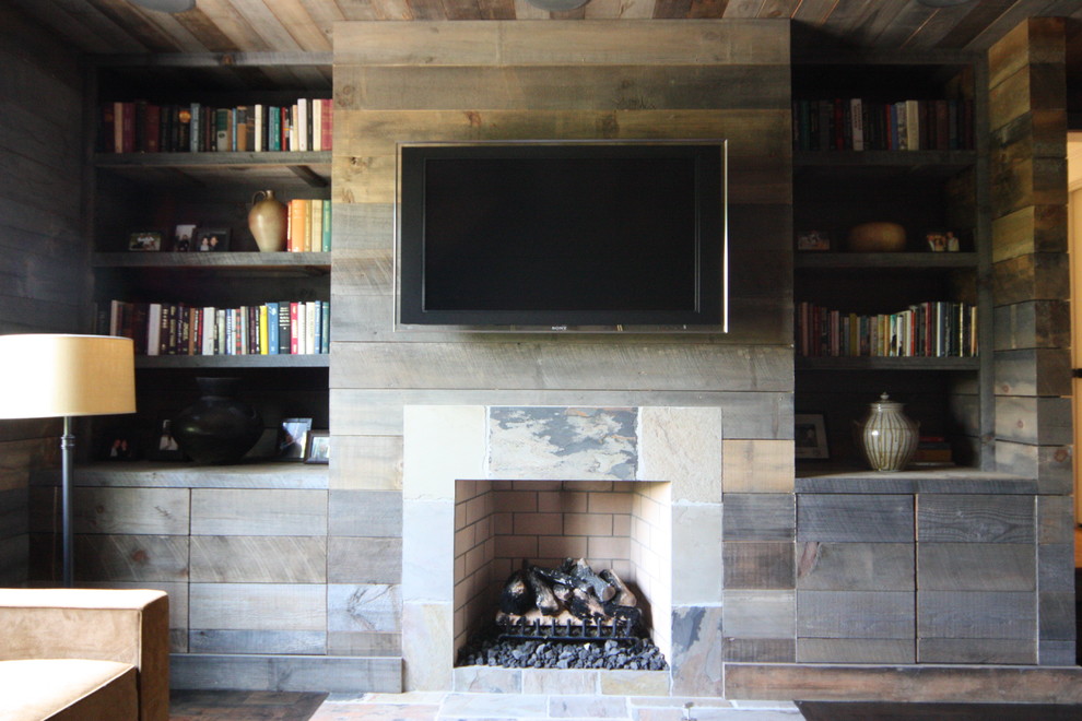 Idée de décoration pour un salon chalet avec une cheminée standard et un téléviseur fixé au mur.