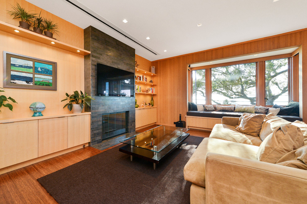 This is an example of a large contemporary open plan living room in San Francisco with medium hardwood flooring, a standard fireplace, a stone fireplace surround and a wall mounted tv.