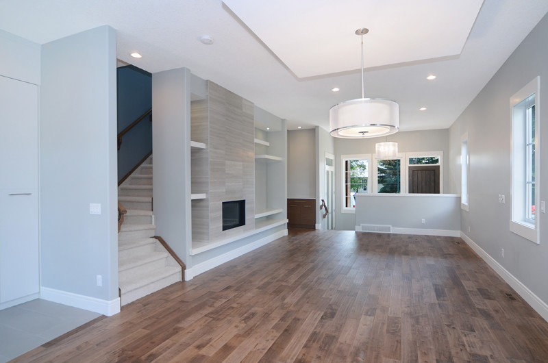 Example of a large minimalist open concept medium tone wood floor living room design in Calgary with gray walls, a ribbon fireplace and a tile fireplace