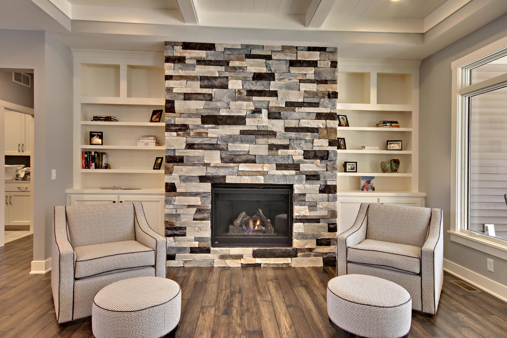 グランドラピッズにある高級な中くらいなコンテンポラリースタイルのおしゃれなLDK (グレーの壁、無垢フローリング、標準型暖炉、石材の暖炉まわり、茶色い床) の写真