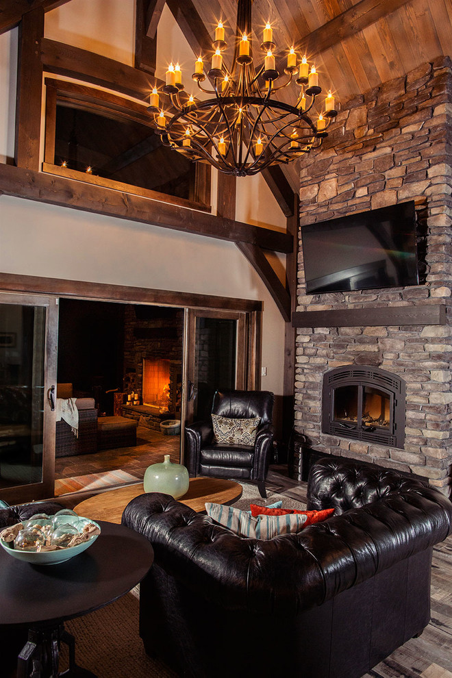 Large mountain style open concept ceramic tile living room photo in Edmonton with beige walls, a wood stove, a stone fireplace and a wall-mounted tv