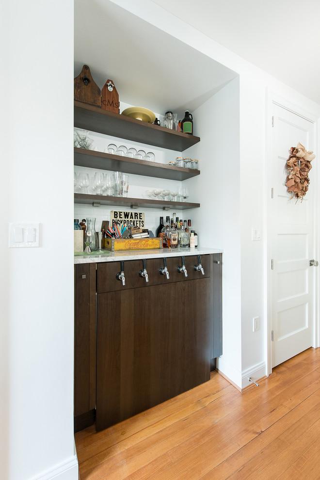 Modelo de salón con barra de bar abierto tradicional renovado con paredes blancas, suelo de madera clara y suelo naranja