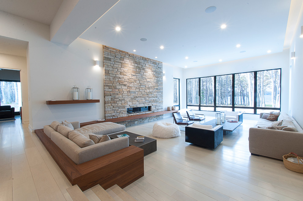 Ejemplo de salón abierto minimalista grande sin televisor con paredes blancas, suelo de madera clara, marco de chimenea de piedra, chimenea lineal y piedra