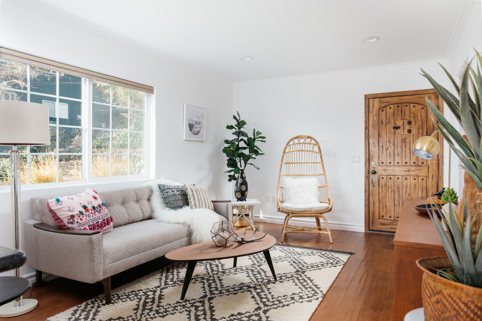 Cette image montre un salon design avec un mur blanc, un sol en bois brun et un sol marron.