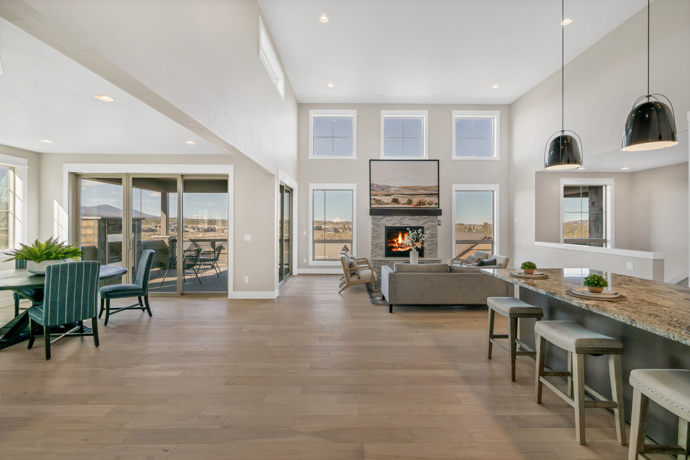 Photo of an expansive classic open plan living room in Portland with grey walls, medium hardwood flooring, a standard fireplace, a stacked stone fireplace surround, brown floors and a vaulted ceiling.