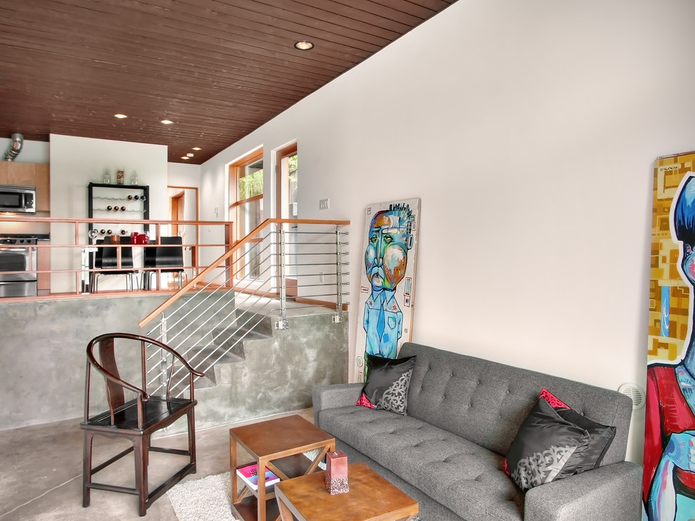 На фото: гостиная комната в стиле модернизм с белыми стенами и бетонным полом с