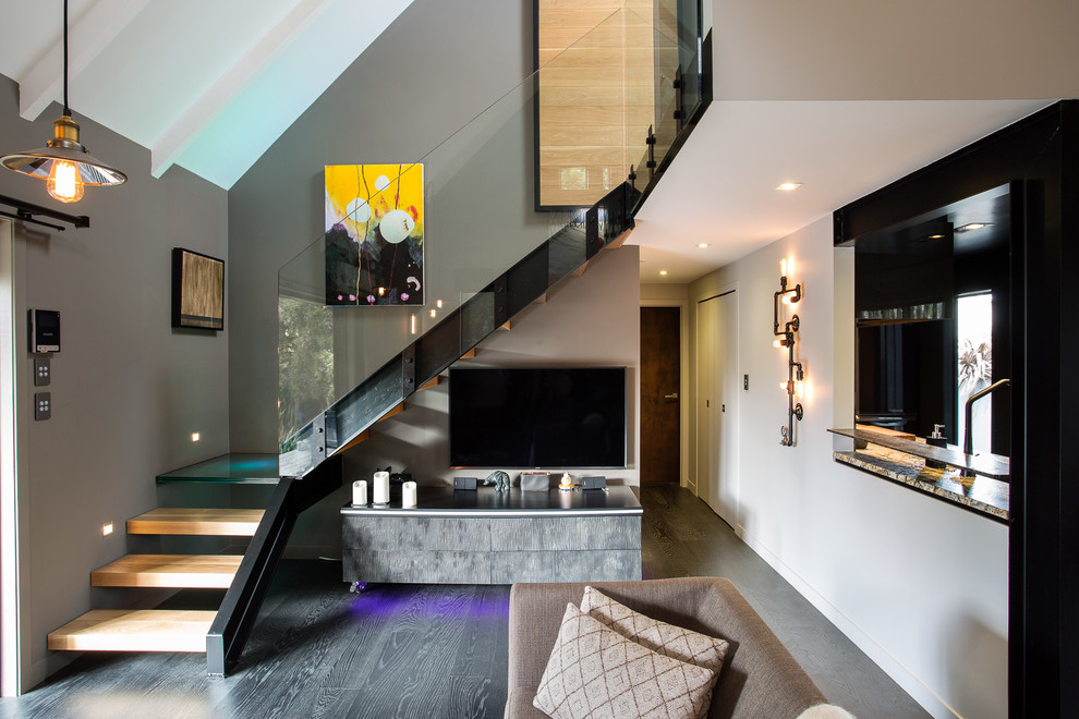 Modelo de salón abierto urbano de tamaño medio con paredes grises, suelo de madera oscura y televisor independiente