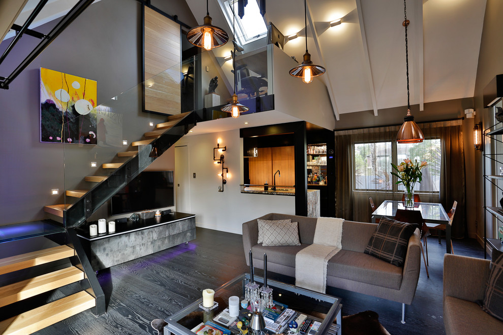 Mittelgroßes, Offenes Industrial Wohnzimmer mit grauer Wandfarbe, dunklem Holzboden und freistehendem TV in Auckland