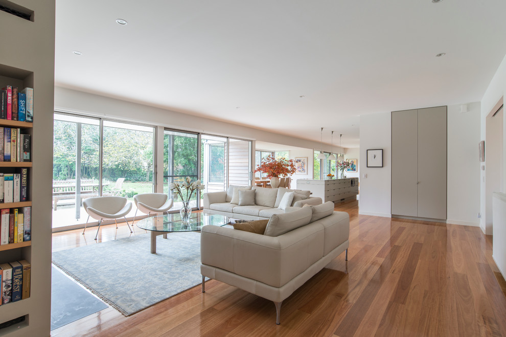 Inspiration for a large contemporary open concept and formal light wood floor living room remodel in Wollongong with a wall-mounted tv, white walls and a brick fireplace