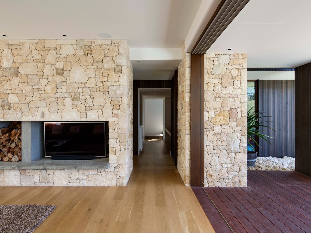 Large formal and open concept light wood floor living room photo in Melbourne with white walls, a standard fireplace, a stone fireplace and a media wall