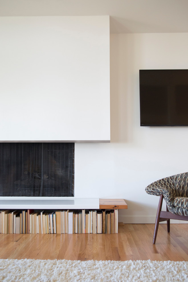 Imagen de salón abierto moderno de tamaño medio con paredes blancas, suelo de madera clara, todas las chimeneas, marco de chimenea de yeso y televisor colgado en la pared