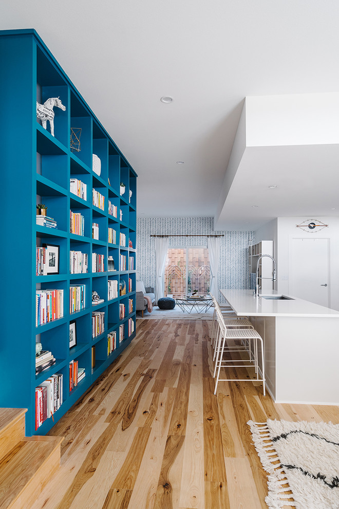 Diseño de biblioteca en casa abierta nórdica grande sin chimenea y televisor con paredes blancas y suelo de madera clara