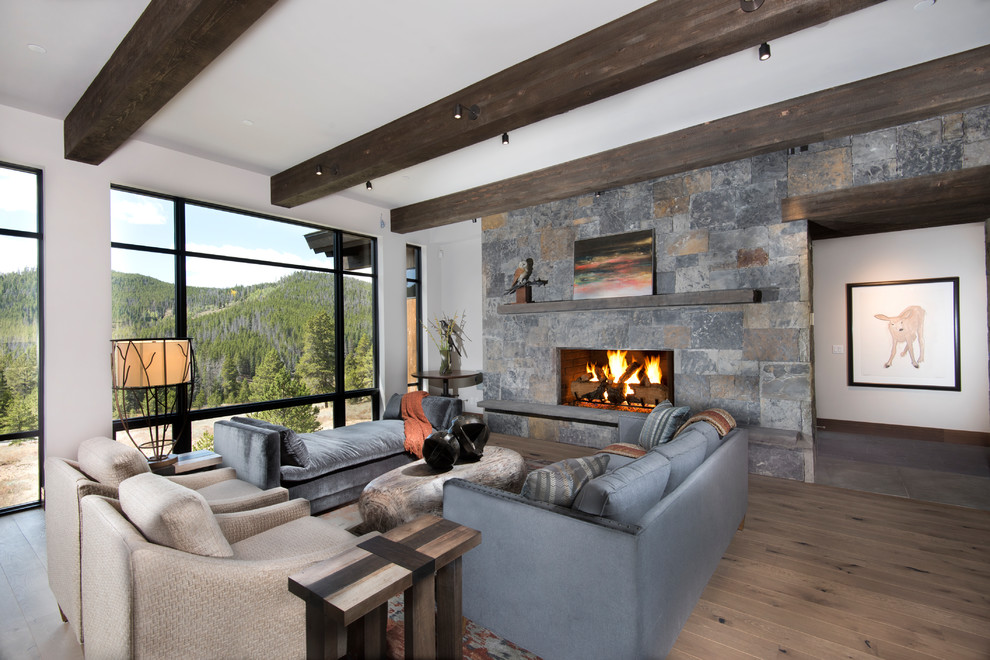 Idées déco pour un salon montagne avec une salle de réception, un mur blanc, parquet foncé, une cheminée standard, un manteau de cheminée en pierre, aucun téléviseur, un sol marron et un mur en pierre.