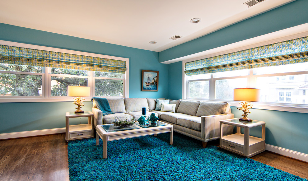 На фото: большая открытая гостиная комната в морском стиле с синими стенами, темным паркетным полом и мультимедийным центром