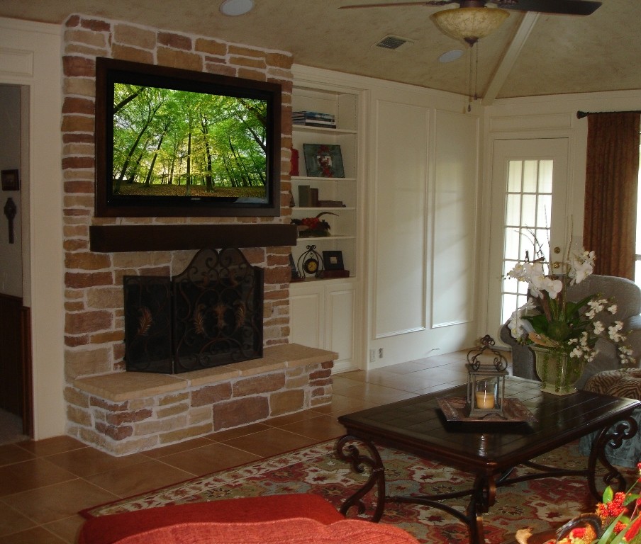 Cette image montre un salon traditionnel de taille moyenne et ouvert avec un sol en carrelage de porcelaine, une cheminée standard, un manteau de cheminée en pierre et un téléviseur encastré.