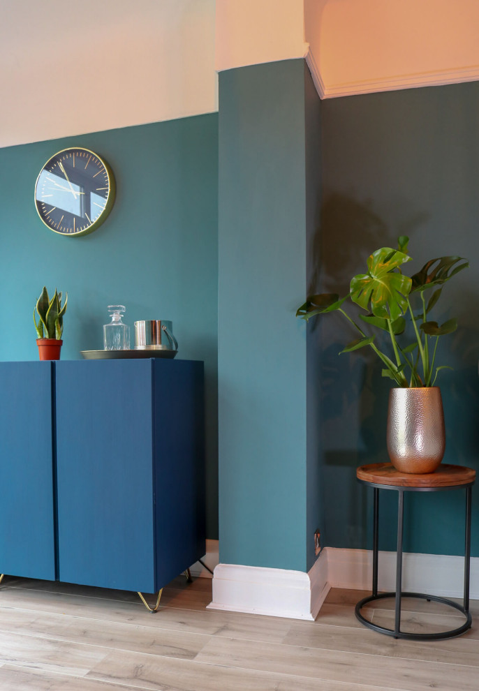 Пример оригинального дизайна: изолированная гостиная комната среднего размера в стиле модернизм с домашним баром, синими стенами, полом из ламината, фасадом камина из дерева, телевизором на стене и коричневым полом без камина