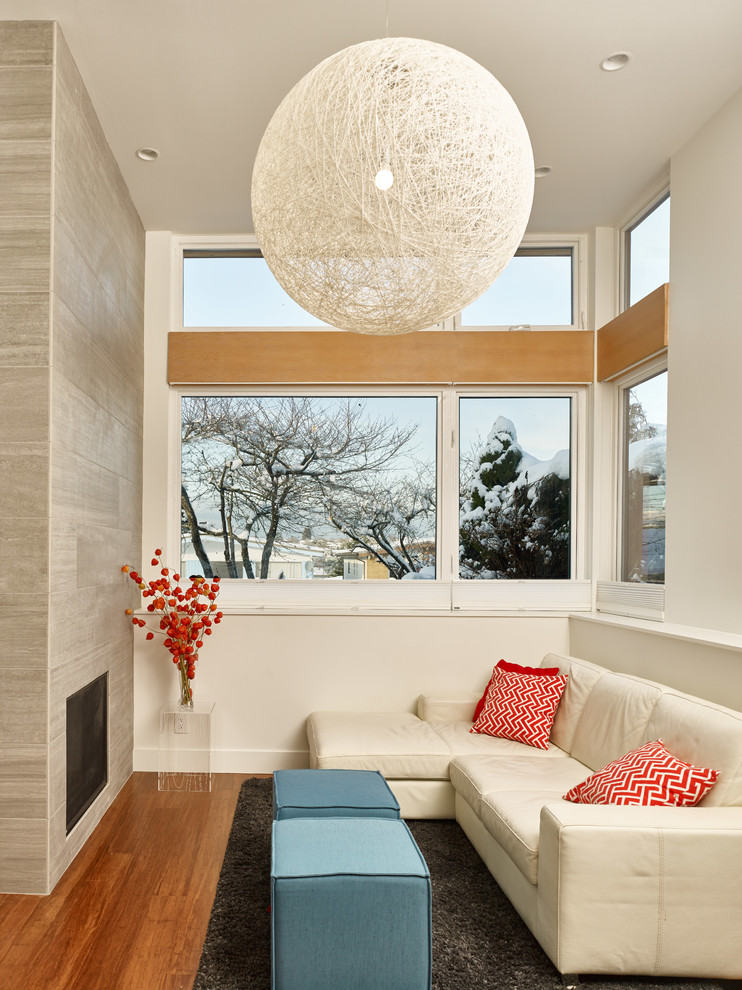 Mittelgroßes, Fernseherloses, Offenes Modernes Wohnzimmer mit weißer Wandfarbe, Bambusparkett, Kamin, gefliester Kaminumrandung und braunem Boden in Vancouver