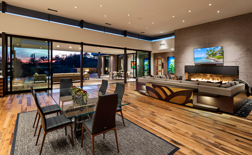 Mediterranes Wohnzimmer mit weißer Wandfarbe, braunem Holzboden, Gaskamin, TV-Wand und braunem Boden in Phoenix