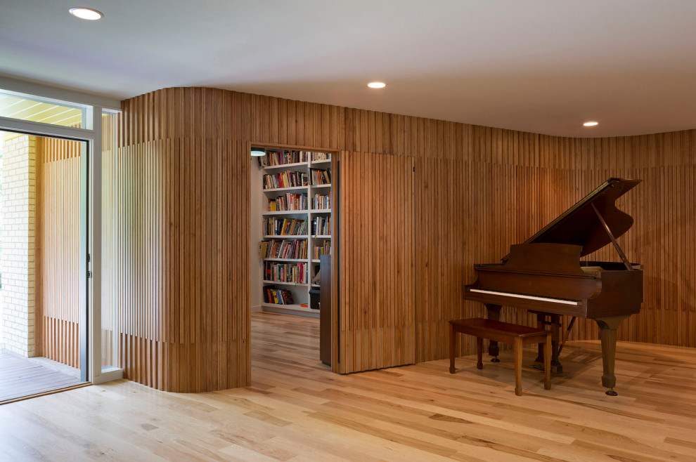 Идея дизайна: большая открытая гостиная комната в стиле модернизм с музыкальной комнатой, коричневыми стенами, светлым паркетным полом, скрытым телевизором, коричневым полом и деревянными стенами без камина