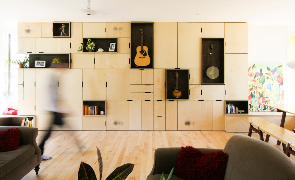 Modelo de biblioteca en casa abierta contemporánea de tamaño medio sin chimenea con suelo de madera clara, televisor retractable y paredes blancas
