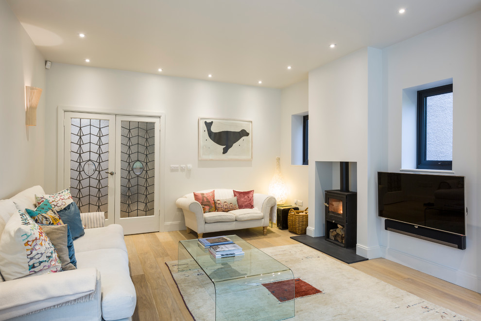 Skandinavisches Wohnzimmer mit TV-Wand, hellem Holzboden, weißer Wandfarbe und Kaminofen in London