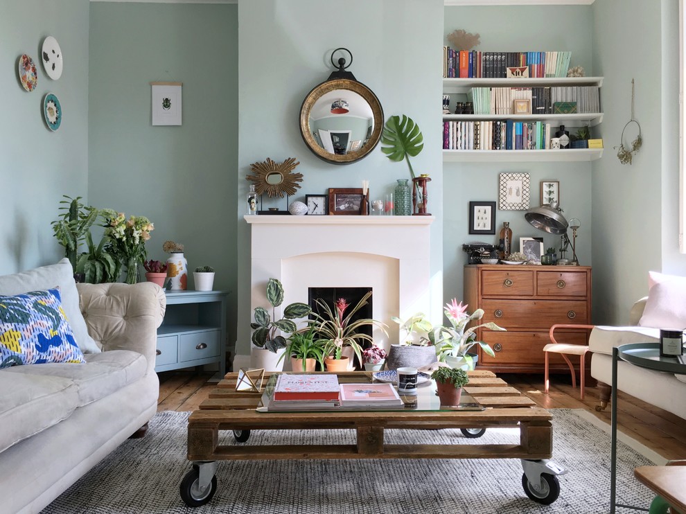 Foto på ett litet eklektiskt separat vardagsrum, med gröna väggar, en standard öppen spis, en spiselkrans i sten, en fristående TV, mellanmörkt trägolv och brunt golv