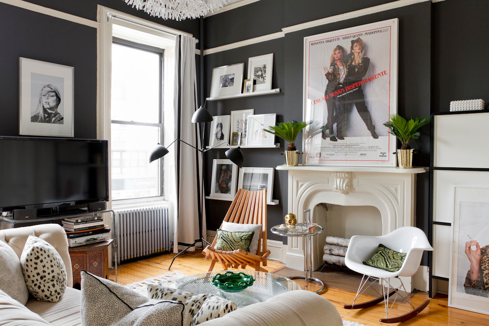 Cette image montre un salon bohème avec un mur noir, un sol en bois brun, une cheminée standard et un téléviseur indépendant.