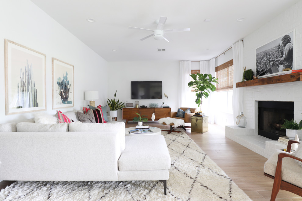 Klassisches Wohnzimmer mit weißer Wandfarbe, Kamin, TV-Wand, beigem Boden, hellem Holzboden und Kaminumrandung aus Backstein in Austin