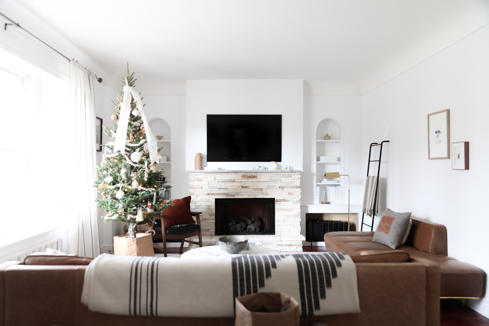 Klassisches Wohnzimmer mit weißer Wandfarbe, braunem Holzboden, Kamin, Kaminumrandung aus Stein, TV-Wand und braunem Boden in Chicago