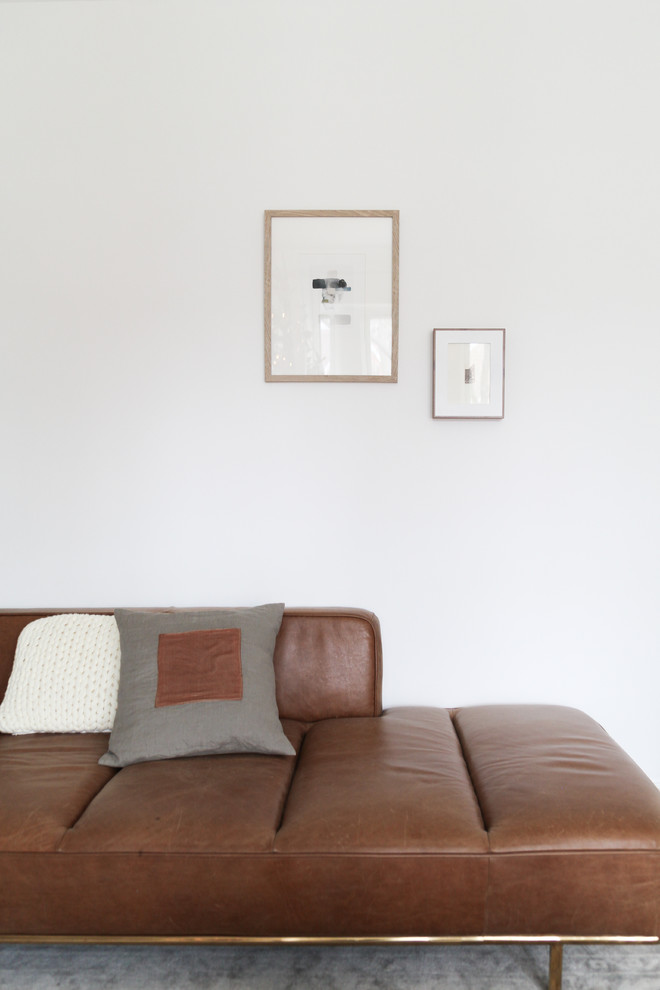 Foto di un soggiorno scandinavo con pareti bianche, pavimento in legno massello medio, camino classico, cornice del camino in pietra, TV a parete e pavimento marrone