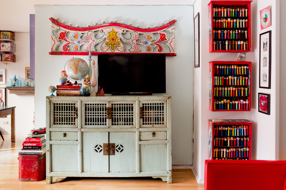 Example of an eclectic medium tone wood floor living room design in New York with white walls and a tv stand