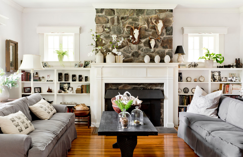 Inspiration pour un salon traditionnel avec un mur blanc, un sol en bois brun, une cheminée standard et un manteau de cheminée en pierre.