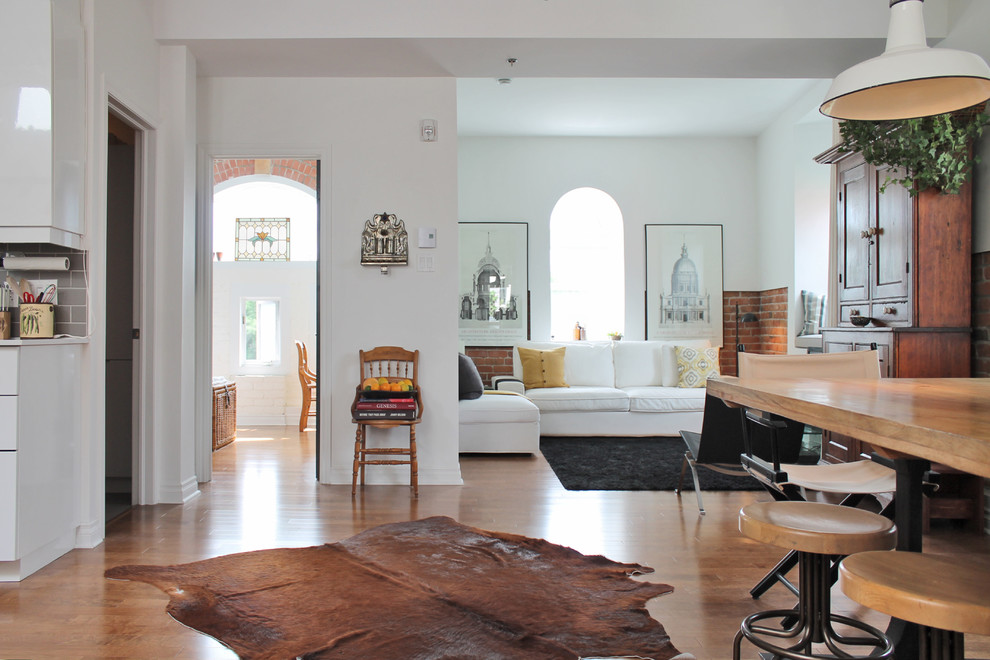 Immagine di un piccolo soggiorno design aperto con pareti bianche, pavimento in legno massello medio, nessun camino e TV autoportante