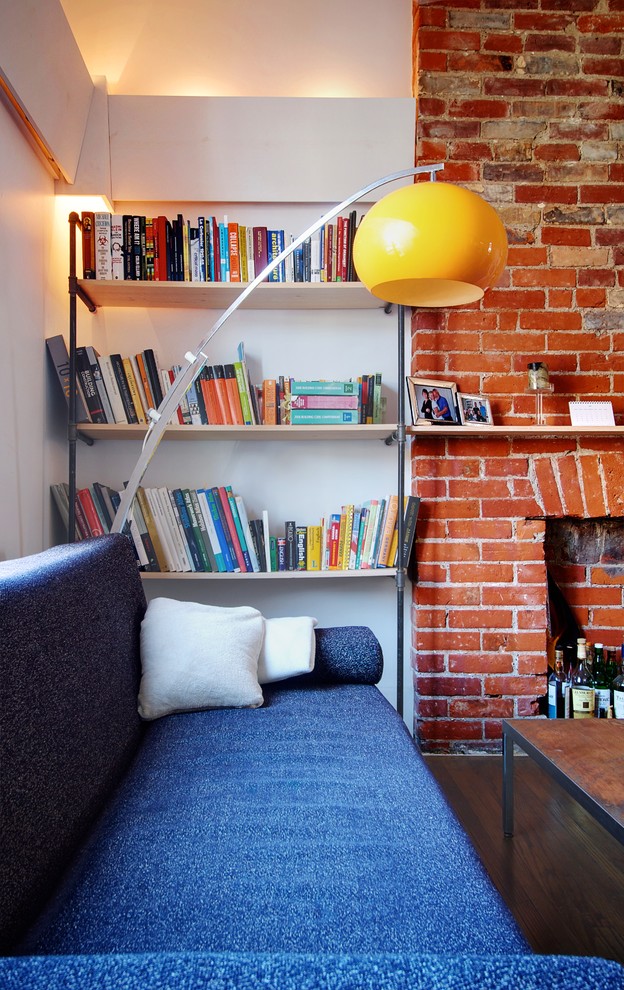 Идея дизайна: гостиная комната в стиле лофт с фасадом камина из кирпича и синим диваном