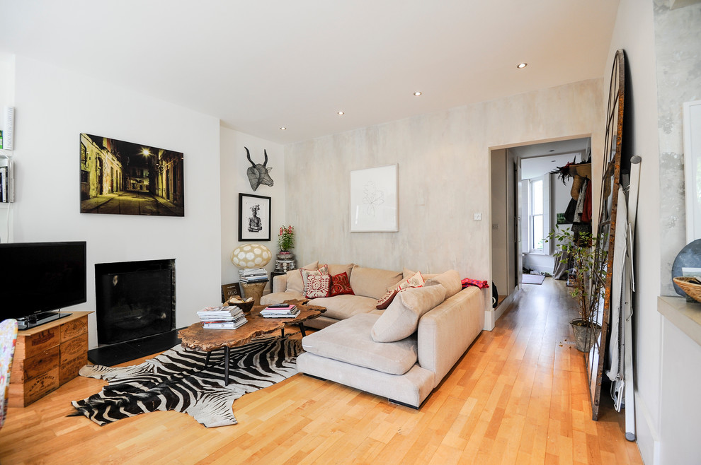 На фото: открытая гостиная комната среднего размера в стиле фьюжн с отдельно стоящим телевизором, серыми стенами, светлым паркетным полом, стандартным камином и фасадом камина из штукатурки