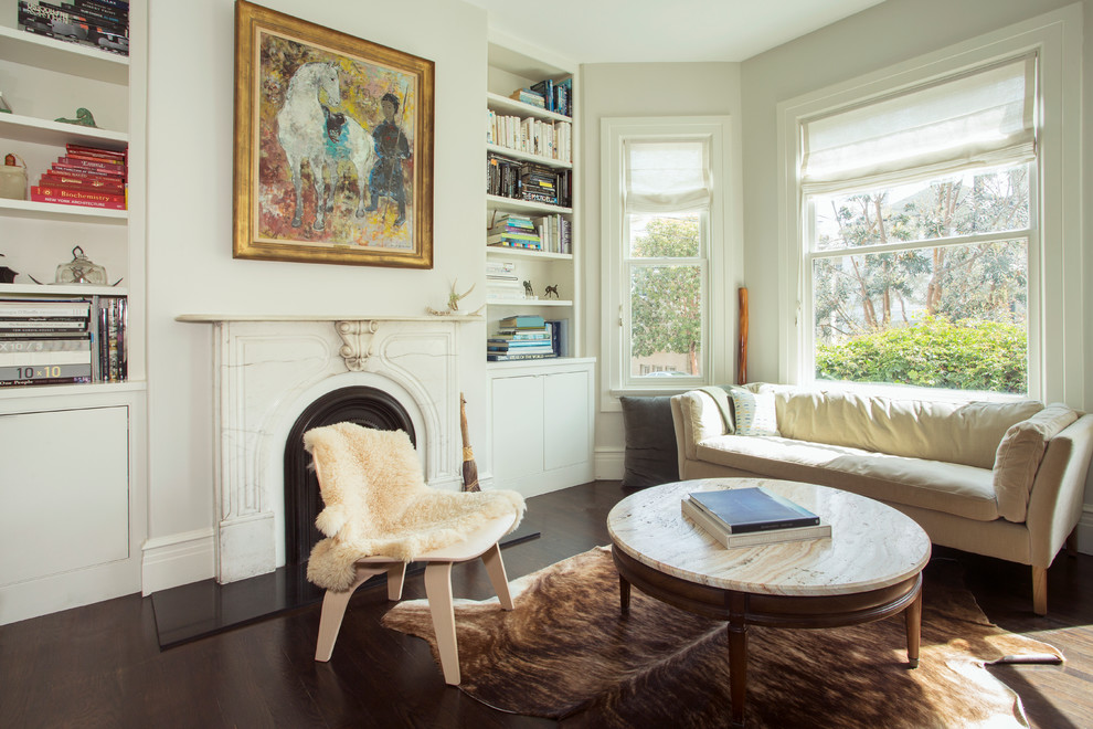 This is an example of a classic living room in San Francisco with white walls, dark hardwood flooring and a standard fireplace.
