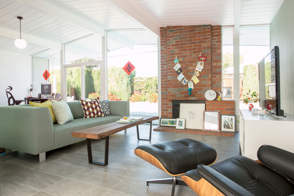 Immagine di un soggiorno minimalista aperto con pareti bianche, camino classico, cornice del camino in mattoni e TV autoportante