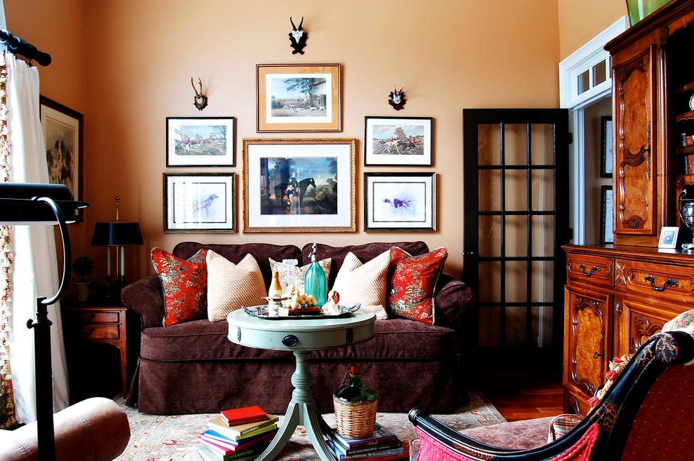 Пример оригинального дизайна: парадная, изолированная гостиная комната в стиле кантри с оранжевыми стенами и бордовым диваном
