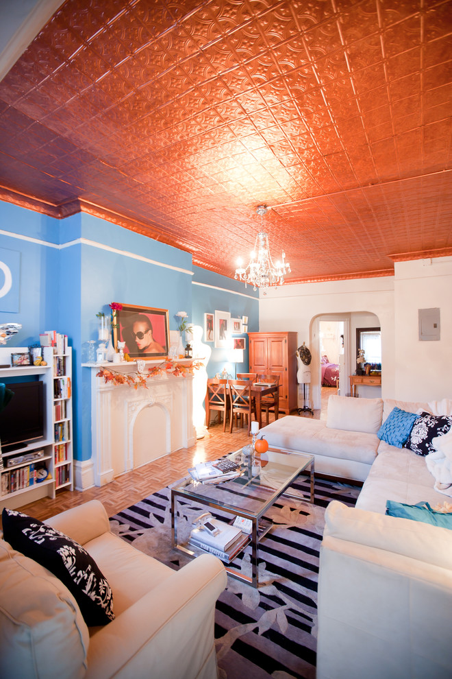 Imagen de salón bohemio con paredes azules y suelo de madera en tonos medios