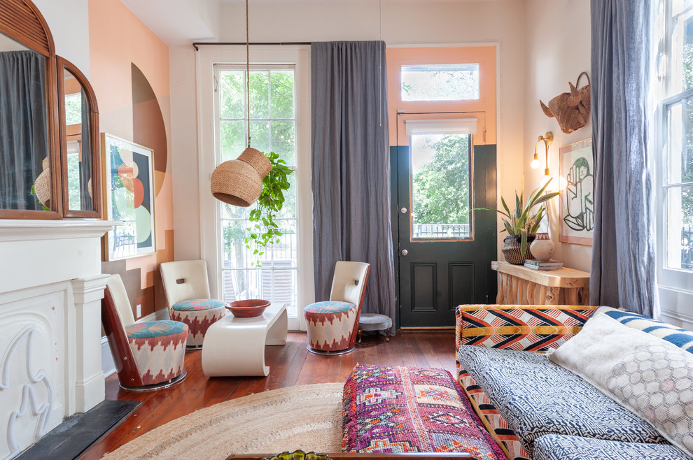 Cette image montre un salon bohème avec un mur multicolore, un sol en bois brun et une cheminée standard.