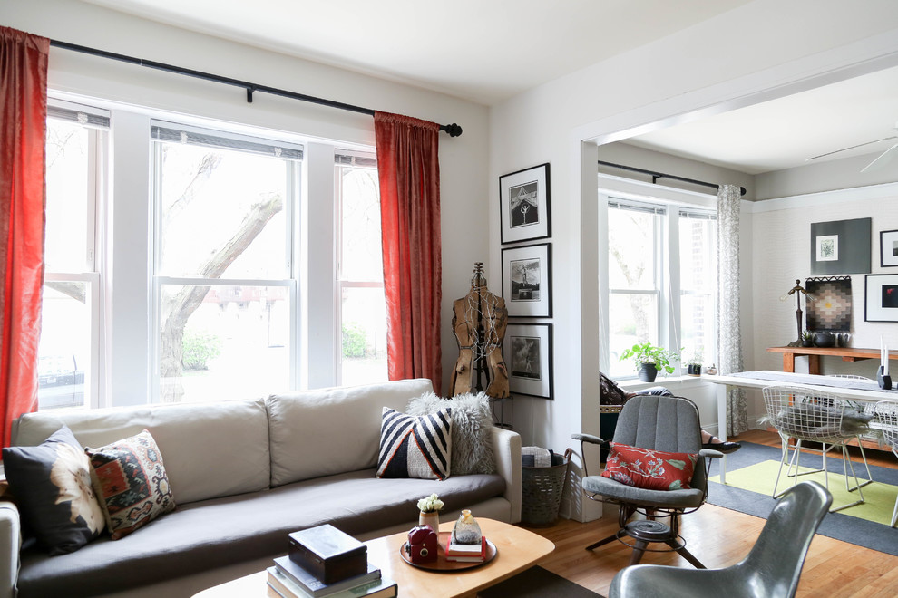 Bohemian open plan living room in Chicago with white walls, medium hardwood flooring and beige floors.