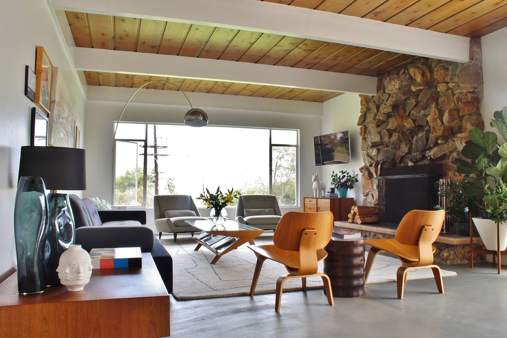 Inspiration for a 1960s formal and open concept concrete floor living room remodel in Los Angeles with white walls, a standard fireplace, a stone fireplace and a wall-mounted tv