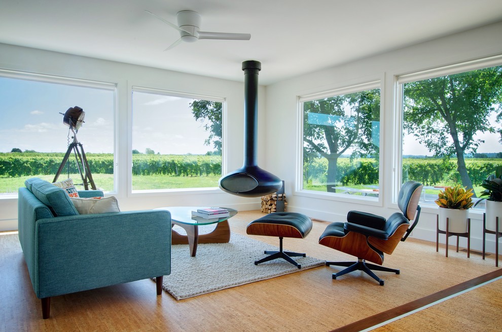 На фото: гостиная комната в современном стиле с пробковым полом, подвесным камином, белыми стенами и синим диваном без телевизора