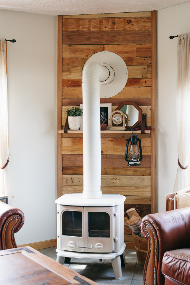 シアトルにある低価格の中くらいなカントリー風のおしゃれな独立型リビング (白い壁、無垢フローリング、薪ストーブ、木材の暖炉まわり) の写真