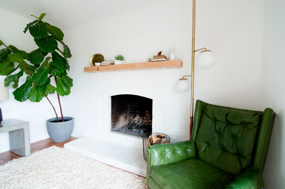 Esempio di un soggiorno minimalista di medie dimensioni e aperto con pareti bianche, parquet chiaro, camino classico, cornice del camino in mattoni e nessuna TV