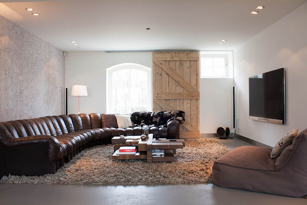 Cette image montre un salon design avec sol en béton ciré, aucune cheminée et un téléviseur fixé au mur.