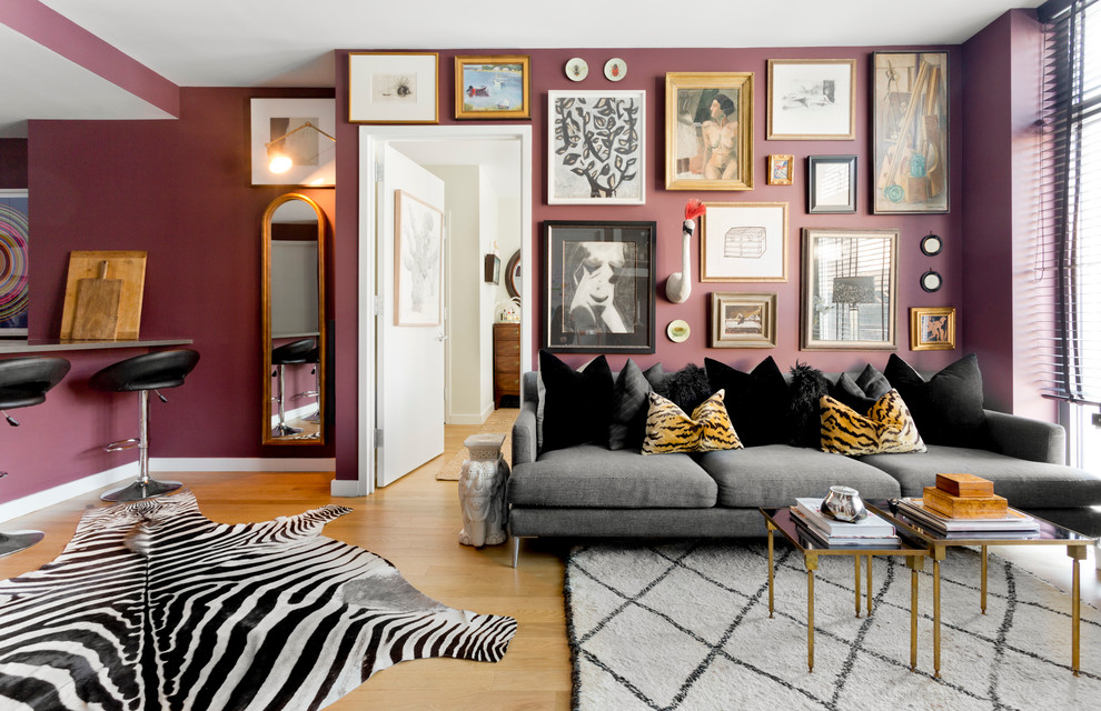 Идея дизайна: открытая гостиная комната в стиле фьюжн с фиолетовыми стенами и светлым паркетным полом