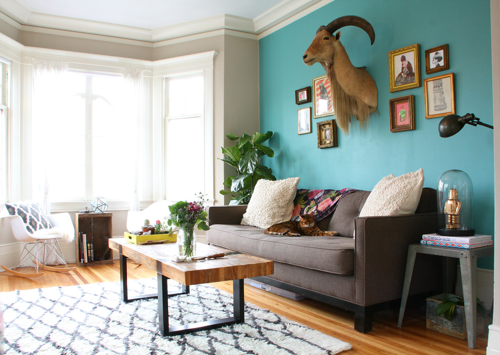 Cette photo montre un salon éclectique fermé avec un mur bleu et un sol en bois brun.